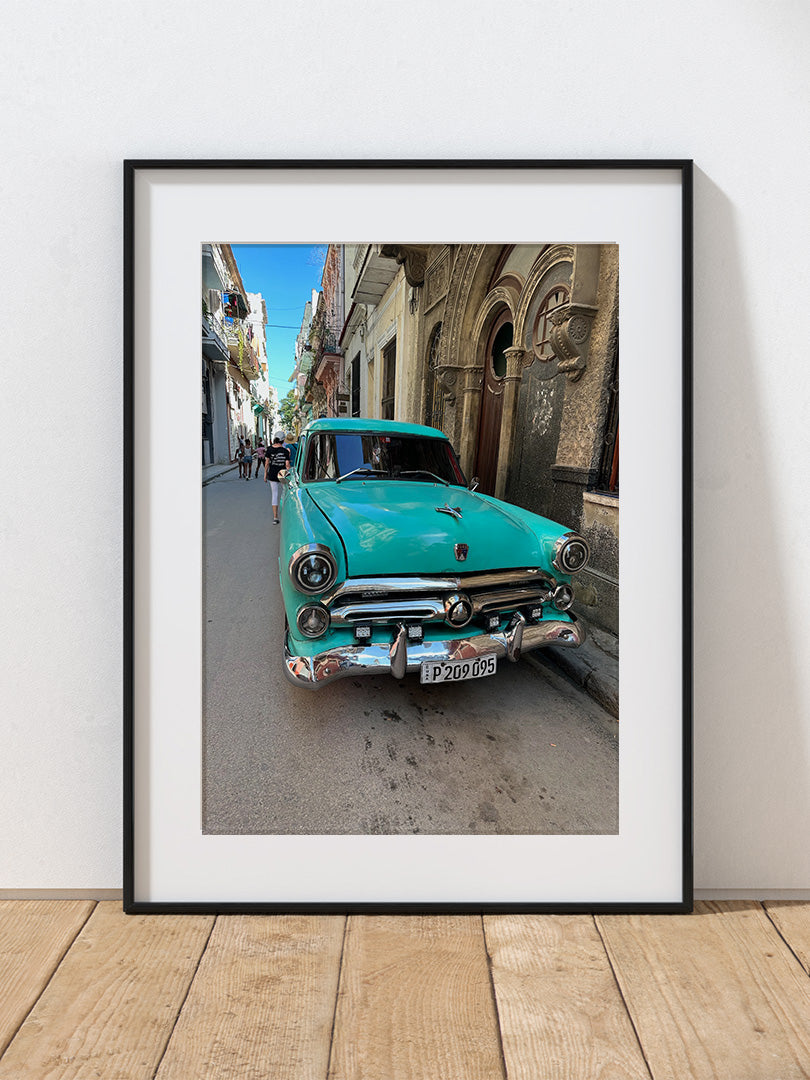 A photograph of a turquoise vintage car on a street in Havana.