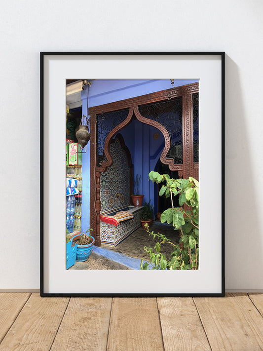 A photograph of a colorful interior with a decorative archway and plants on a wooden floor in Morocco